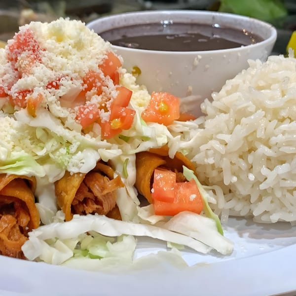 Peruvian taquitos topped with lettuce, tomatoes, and cheese, served with rice and black beans.